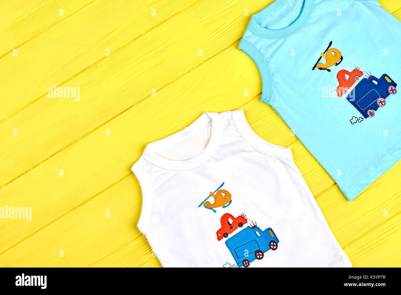 Garçons Vêtements pour bébé de couleur d'été. série de dessin animé à la  mode t-shirts pour tout-petits garçons sur fond de bois jaune, vue d'en  haut. en vente de vêtements d'été pour