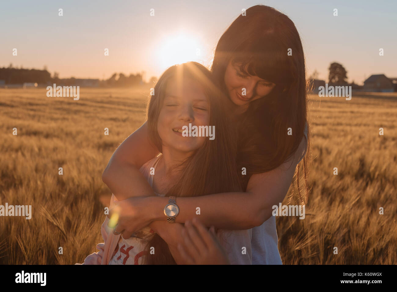 Maman hugging her daughter dans le champ jaune. Banque D'Images