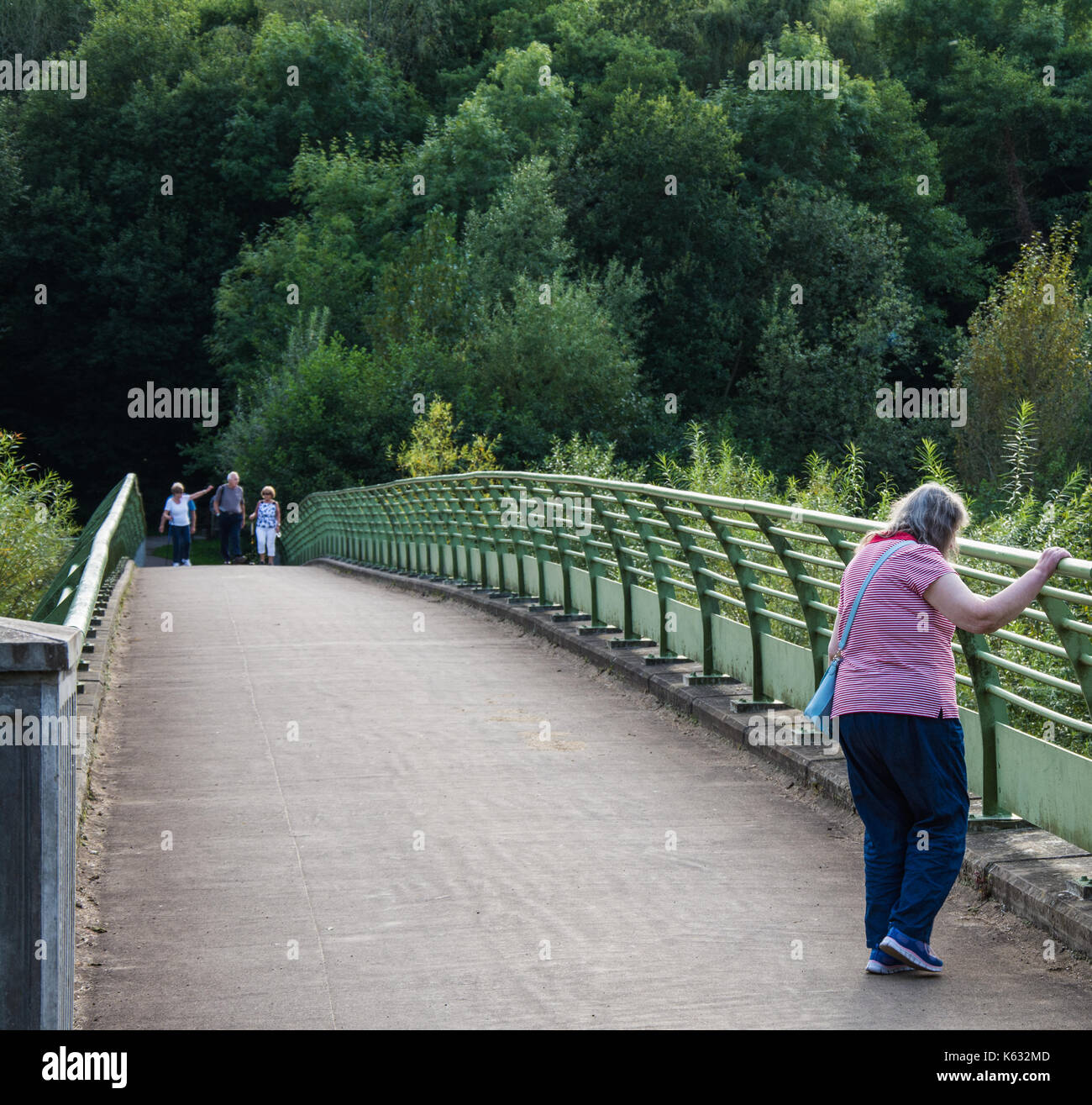 Une femme âgée se tient sur la passerelle au-dessus de la rivière Severn à la Severn Valley Country Park, Alveley, Shropshire, au Royaume-Uni. Banque D'Images