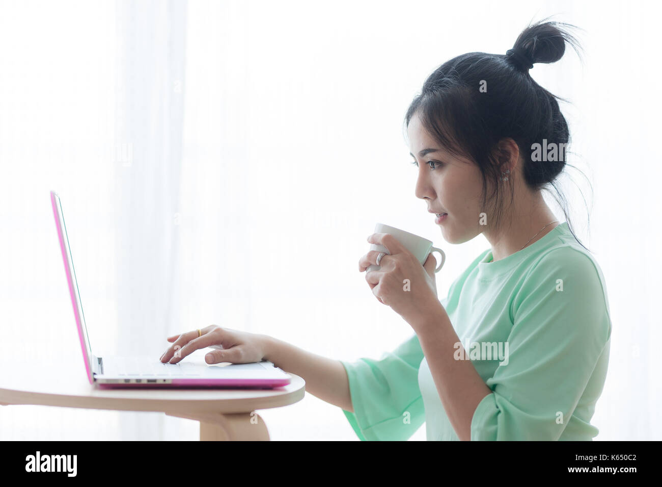 Young attractive asian woman holding Coffee cup indépendant tout en travaillant avec un ordinateur portable. travailler à la maison et de l'apprentissage en ligne concept Banque D'Images