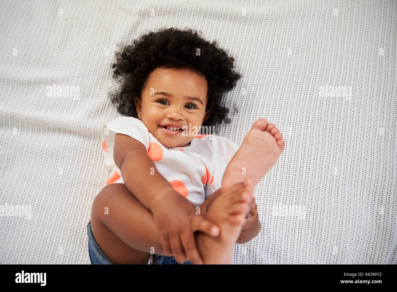Coup de frais généraux de Smiling Baby Girl Lying On Bed Banque D'Images