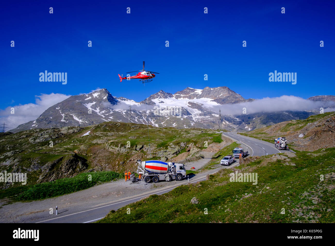 Un hélicoptère de la société Swiss Helicopters transporte du béton vers un chantier de construction dans les montagnes depuis le col de Bernina, Passo del Bernina Banque D'Images