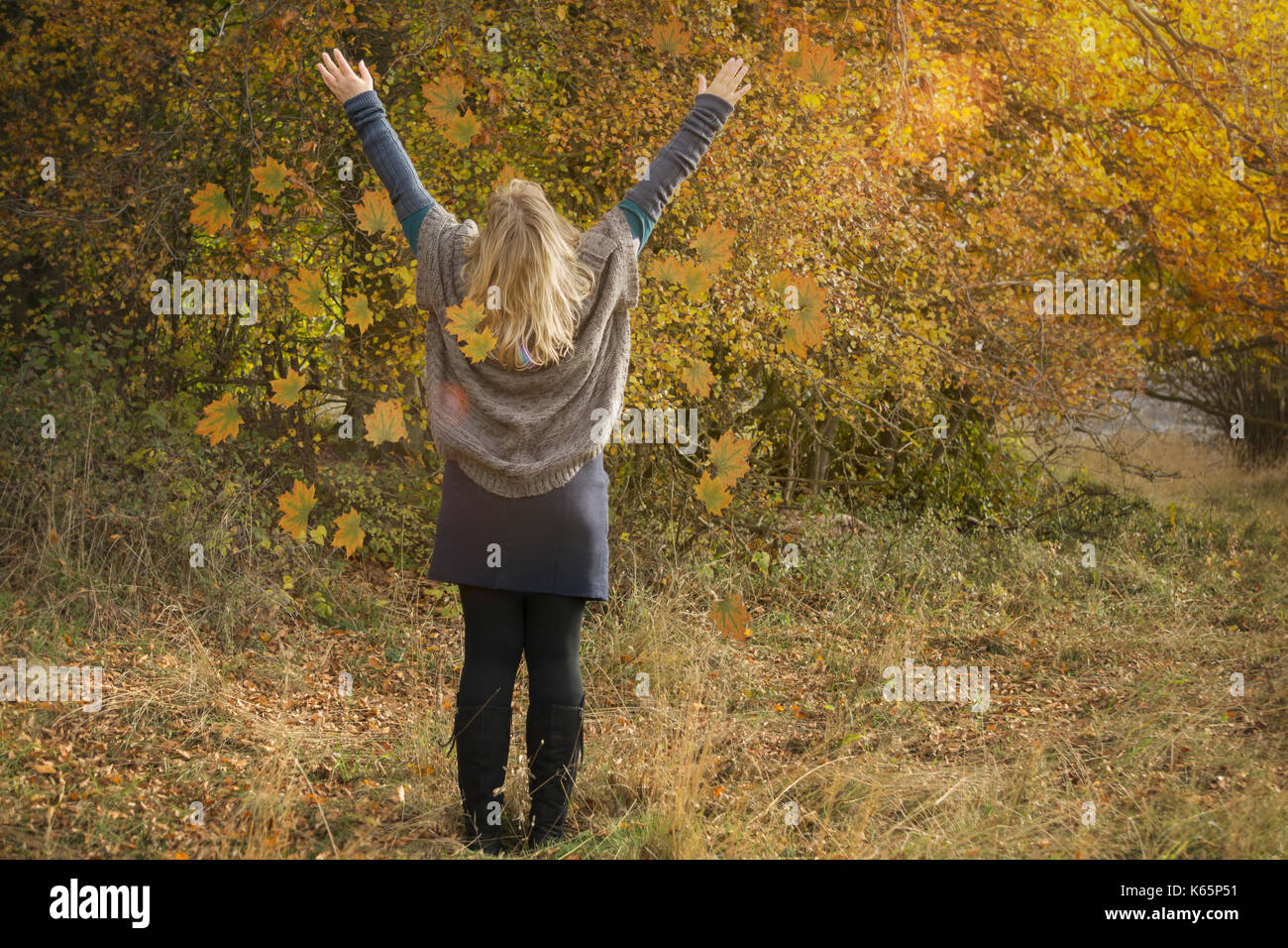 Femme avec de longs cheveux blonds se trouve dans un décor de l'automne et feuilles jette Banque D'Images
