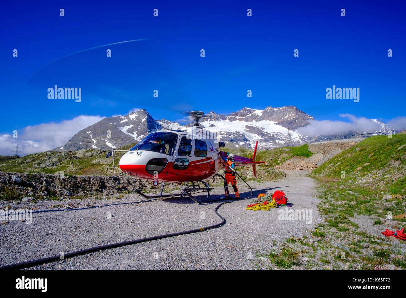 Un travailleur de la société Swiss Helicopters ravitaillera en carburant l'hélicoptère pour transporter du béton vers un chantier de construction dans les montagnes depuis Bernina Banque D'Images