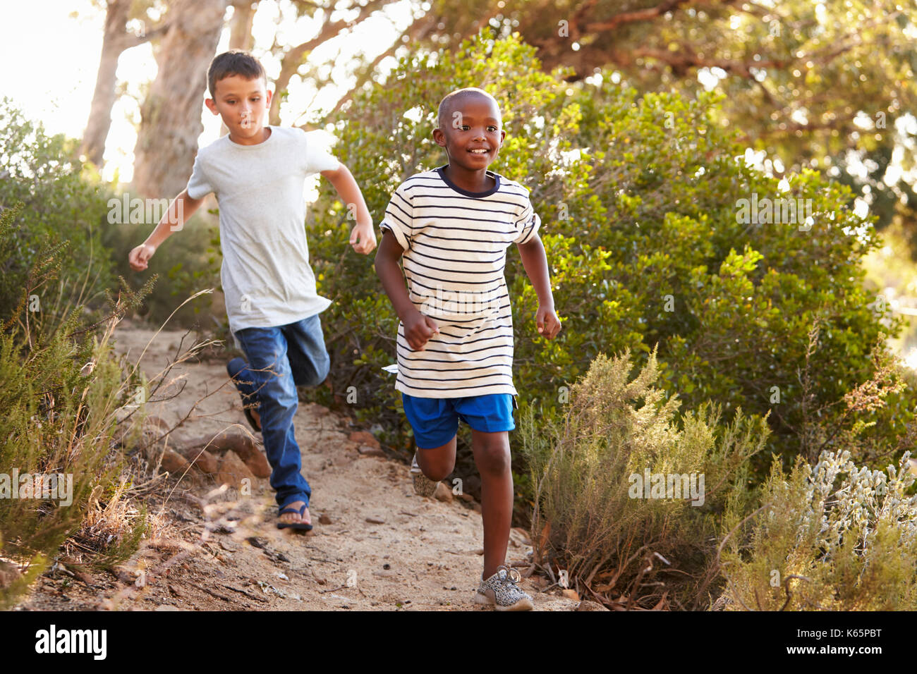 Deux jeunes garçons heureux courant le long d'un chemin forestier Banque D'Images