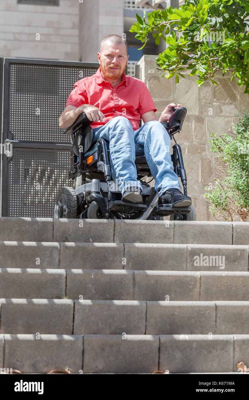 Homme en fauteuil roulant en face de barrière d'escalier Banque D'Images