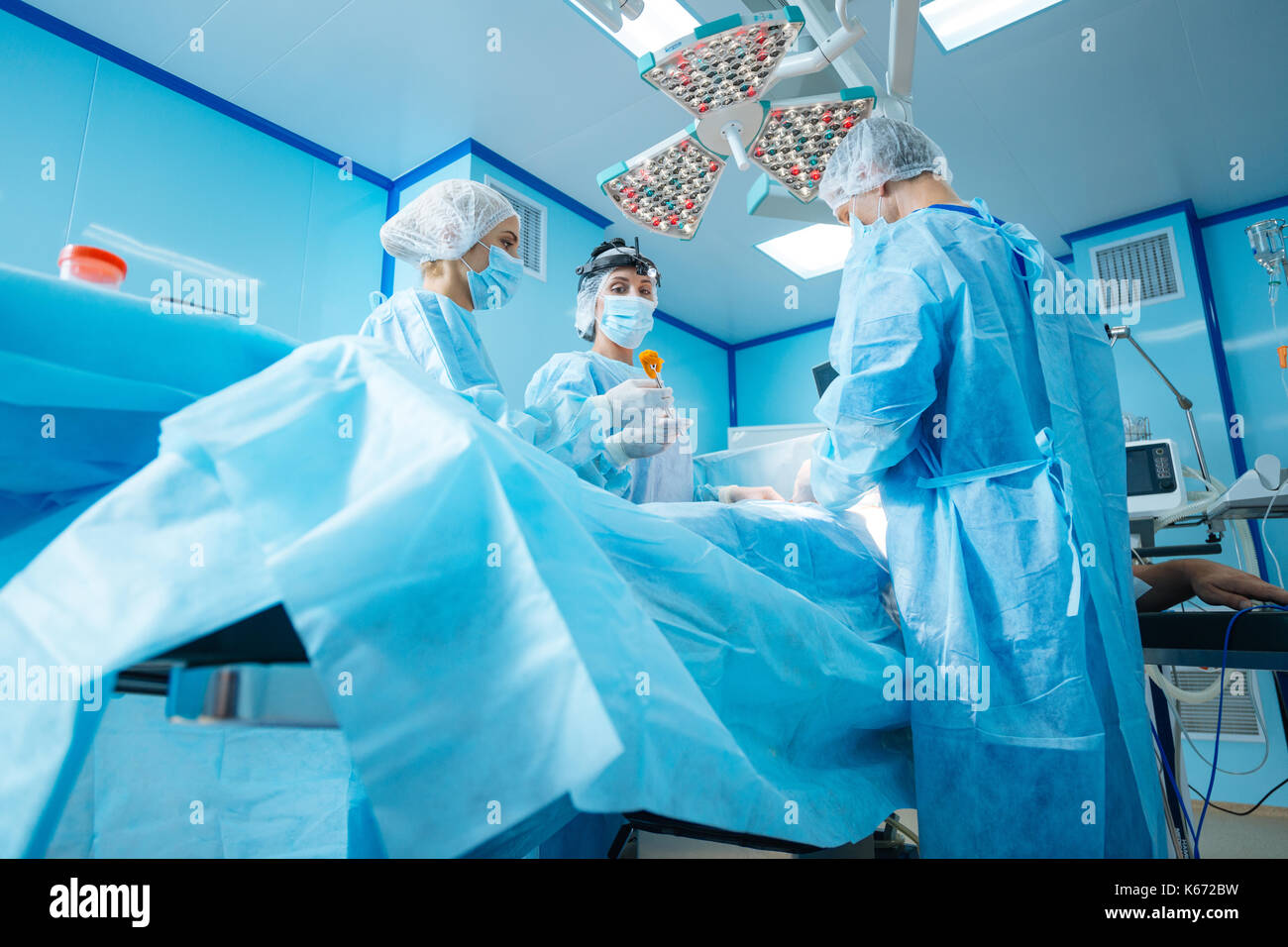 Les médecins sérieux debout autour de la table chirurgicale Banque D'Images