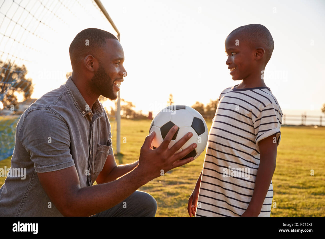 Père donne une balle à son fils pendant un match de football Banque D'Images