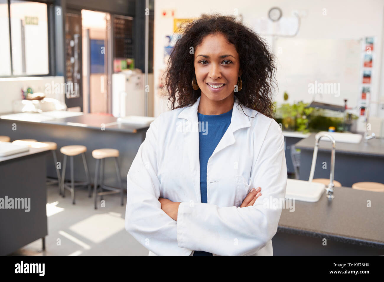 Female teacher in lab coat smiling in school science prix Banque D'Images