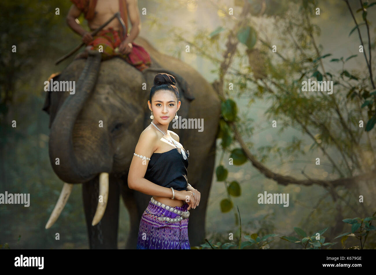 Femme en vêtements traditionnels thaïlandais avec un cornac équitation un éléphant, Thaïlande Banque D'Images