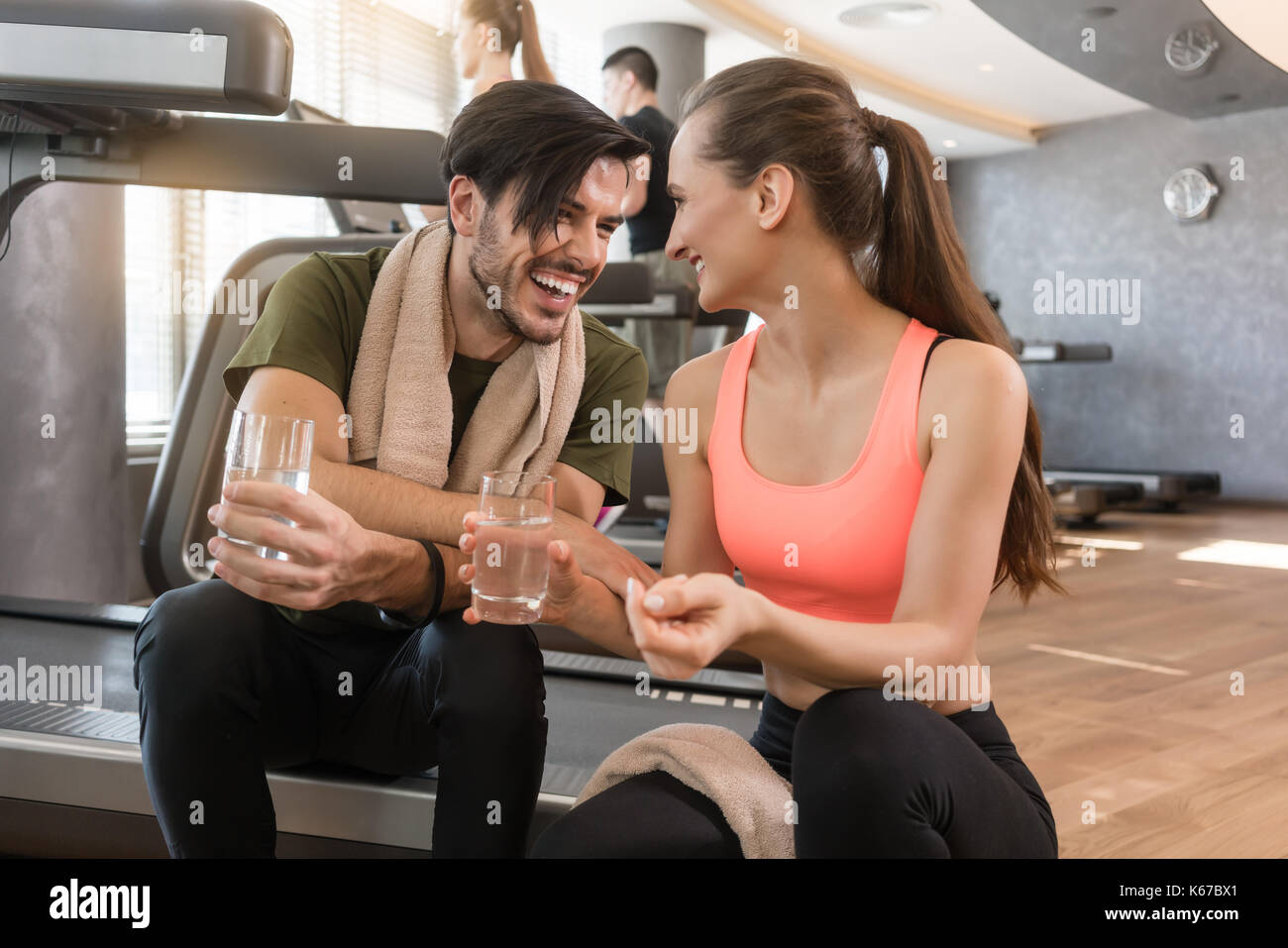 Cheerful young man and woman boire de l'eau claire pendant une pause Banque D'Images