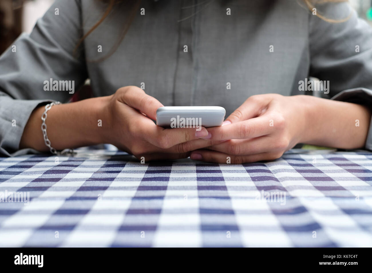 Femme assise à une table à l'aide de son téléphone portable Banque D'Images