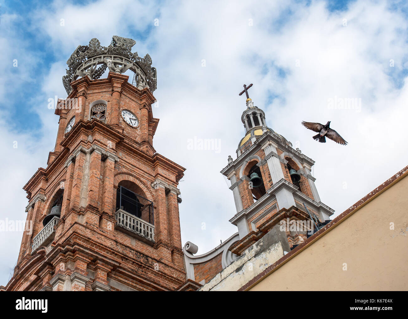 Les clochers de Notre Dame de Guadalupe cathédrale / Eglise dans la vieille ville de Puerto Vallarta comme un oiseau vole contre le ciel comme si symbolisant la paix ou d'espoir Banque D'Images