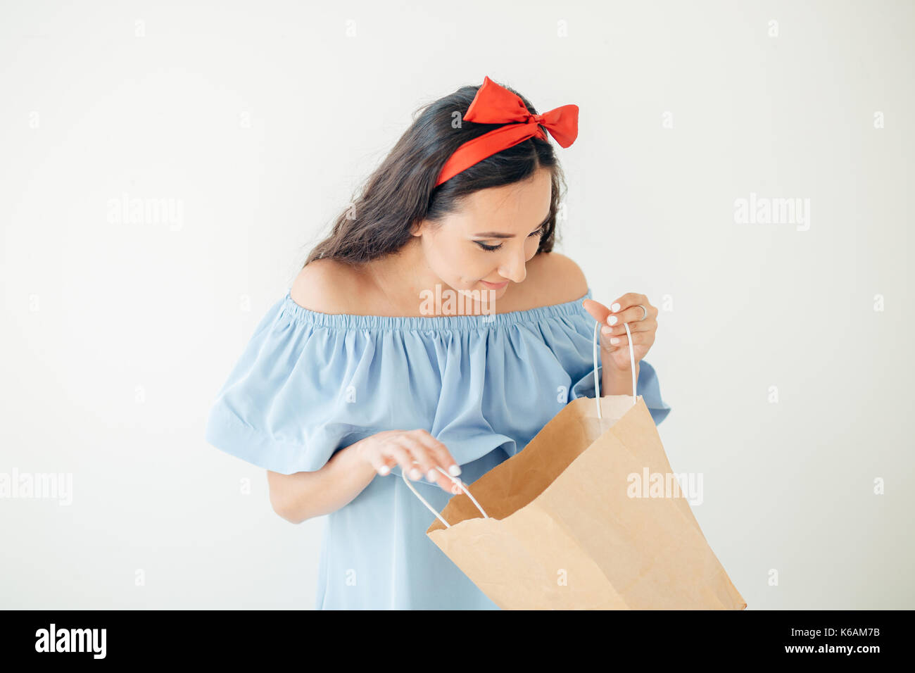 Portrait of cute happy sweet surprise belle femme fille tenant dans ses mains grand sac shopping en vêtements rouges hipster isolated on white Banque D'Images