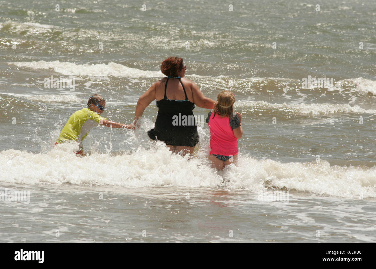 Famille jouant dans les vagues du golfe du Mexique, la péninsule de Bolivar, Texas Banque D'Images
