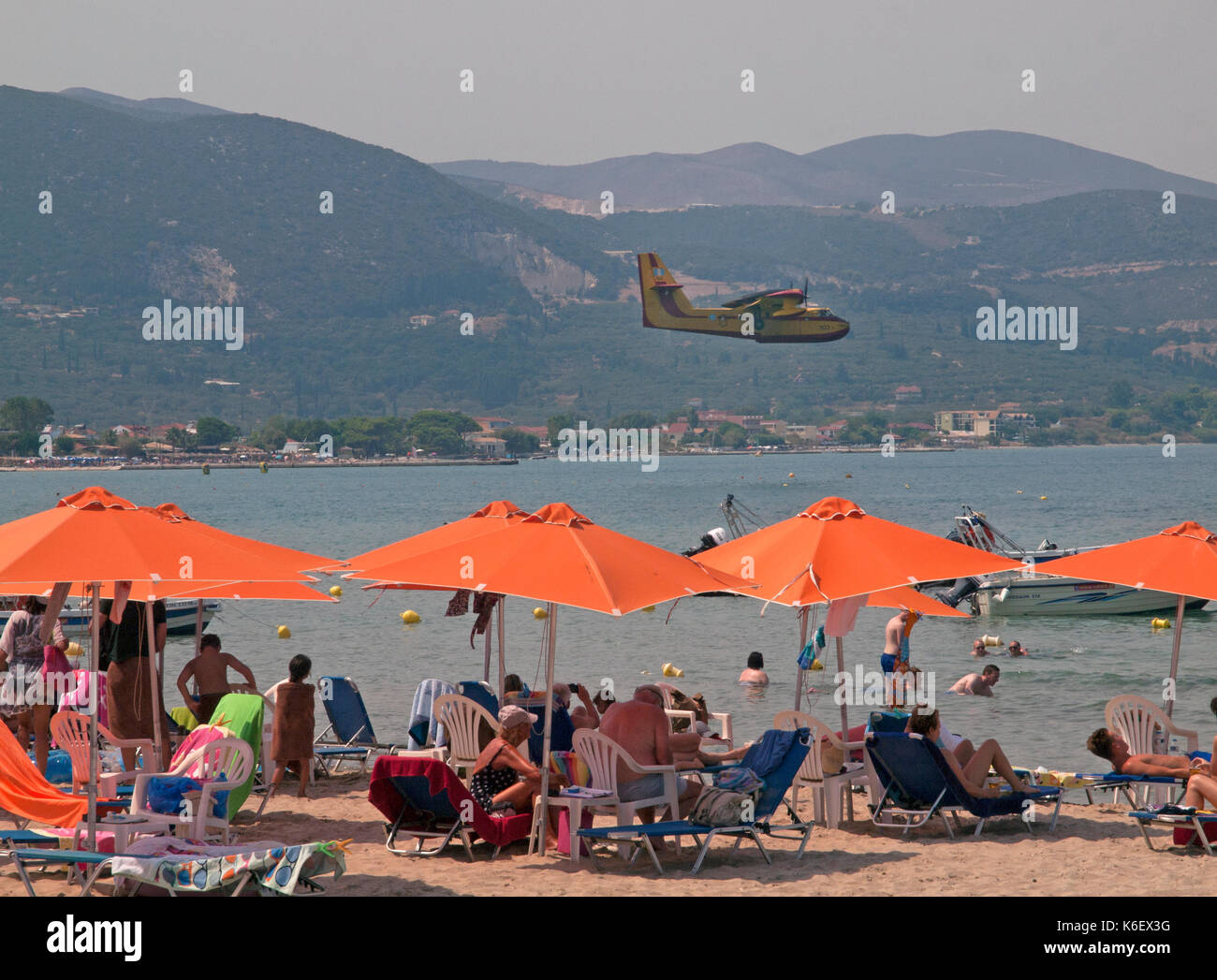 Au-dessus de la plage de Kallithea un avion vient dans de recueillir l'eau pour éteindre les incendies dans les collines Banque D'Images