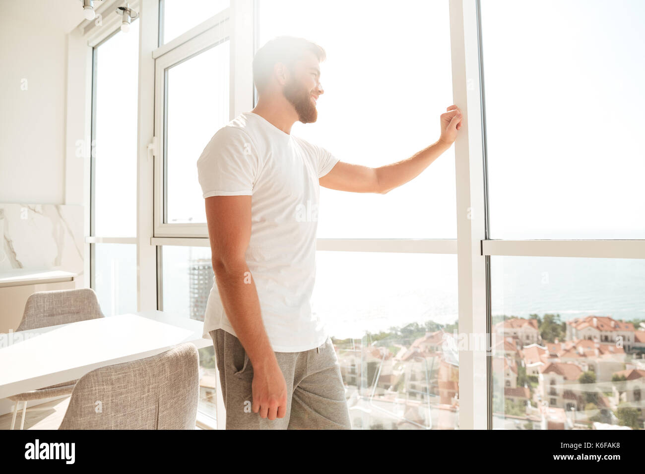 Vue latérale du beau barbu regardant la fenêtre à la maison Banque D'Images