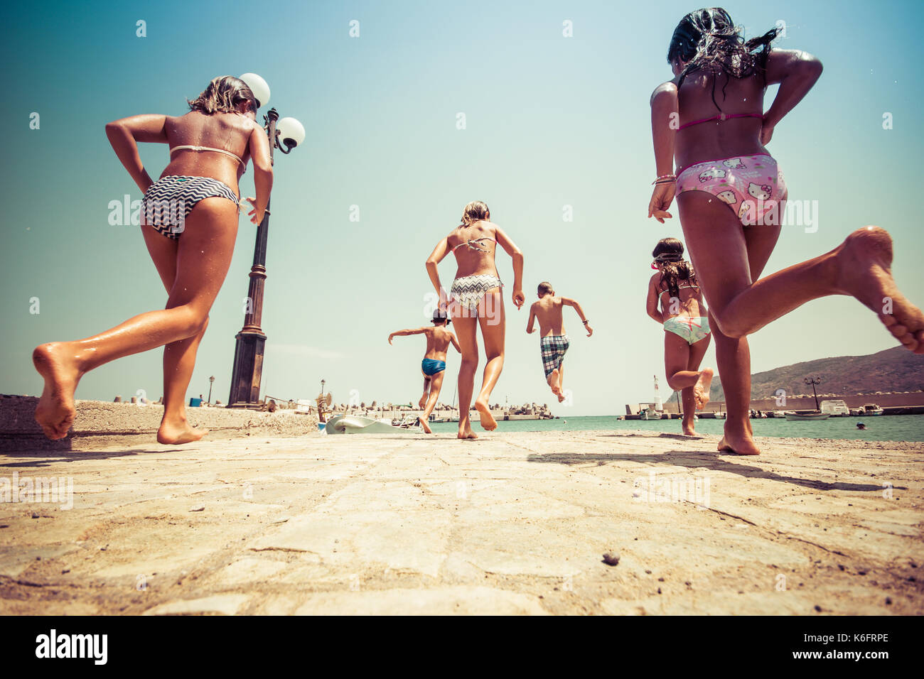 Groupe d'amis de sauter à la mer de la jetée, happy beach holidays, Crète, Grèce Banque D'Images