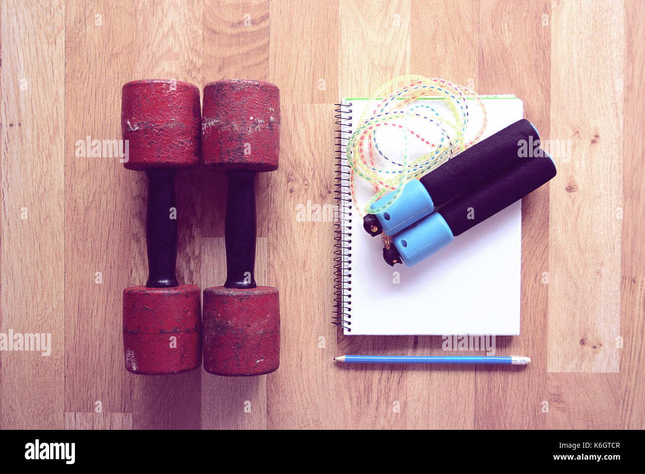 Dumbells et corde avec un carnet et un stylo pour prendre des notes sur la maison d'entraînement. Vue de dessus et copie vide de l'espace pour l'éditeur de texte. Banque D'Images
