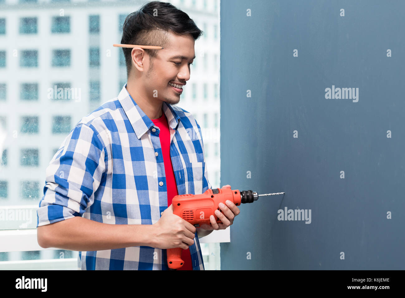 Asian do-it-yourself handyman drilling Banque D'Images
