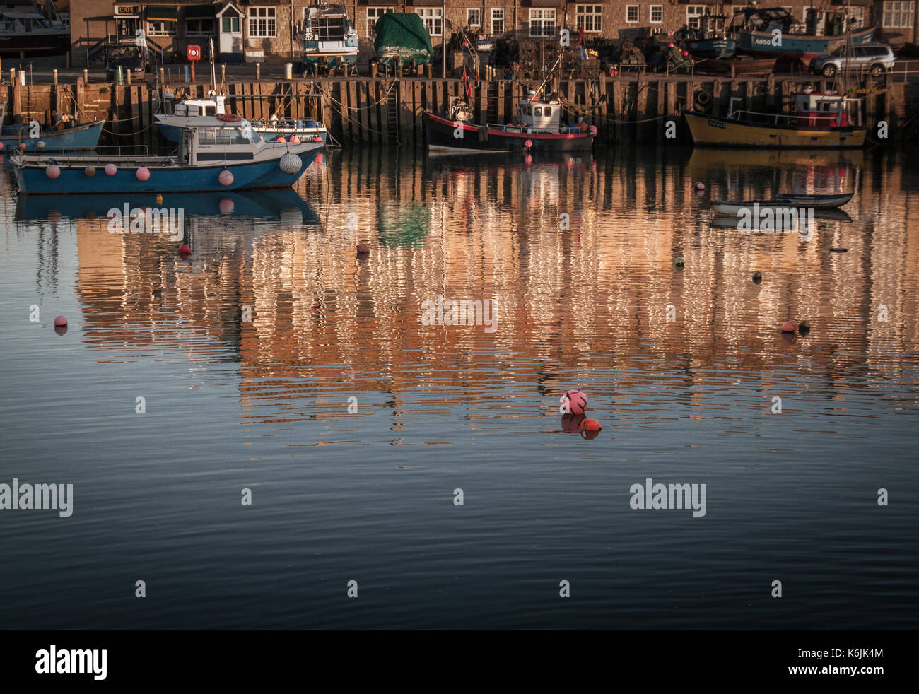 Bateaux dans le port de West Bay, près de Bridport, Dorset, juste avant le coucher du soleil. Couleurs vives et reflets dans l'eau. Banque D'Images