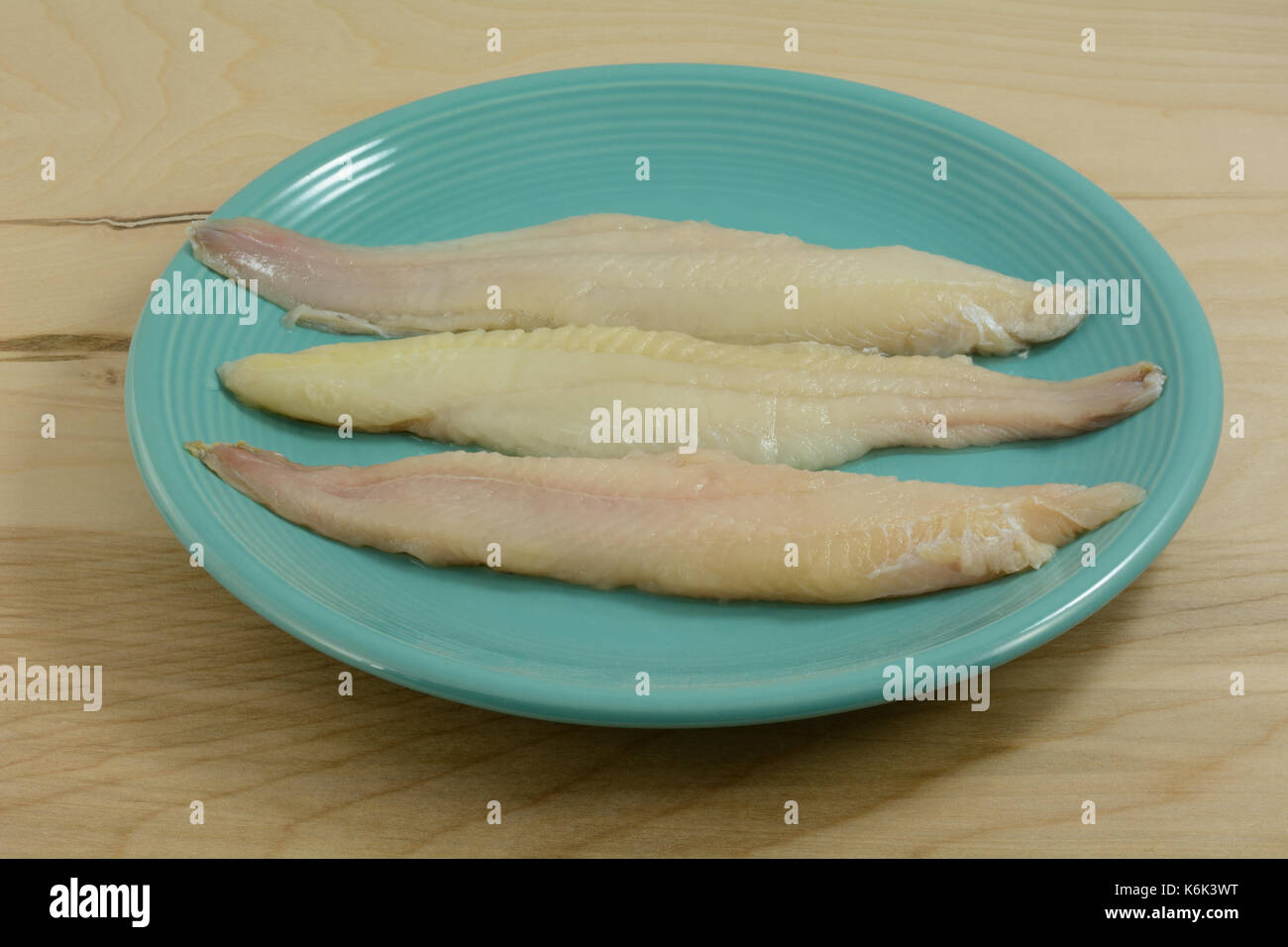 Rincer les filets de poisson-chat trois matières premières sur plaque bleue en préparation pour la cuisson Banque D'Images