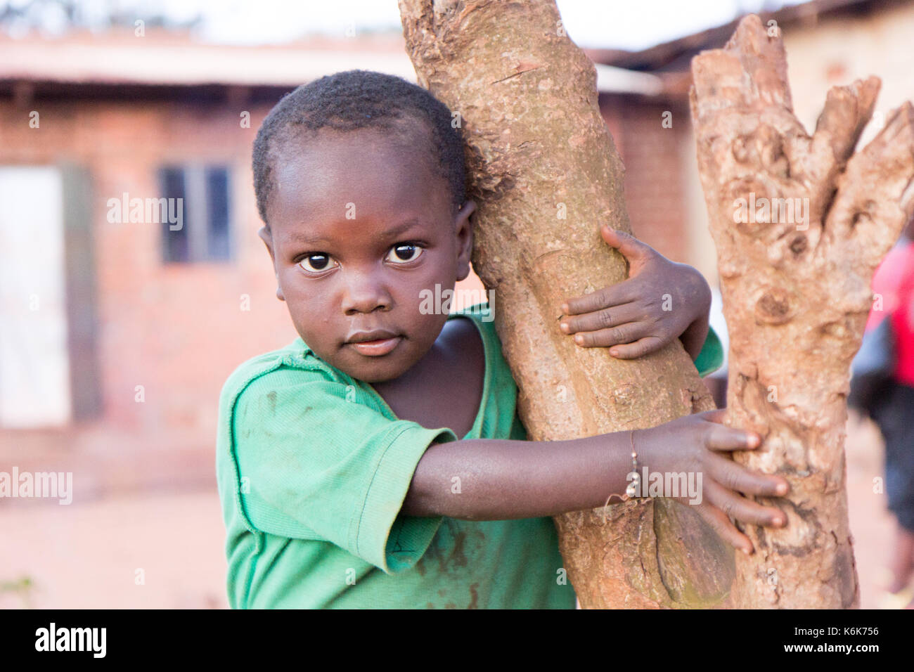 Un petit enfant noir accroché à un tronc d'arbre. Banque D'Images