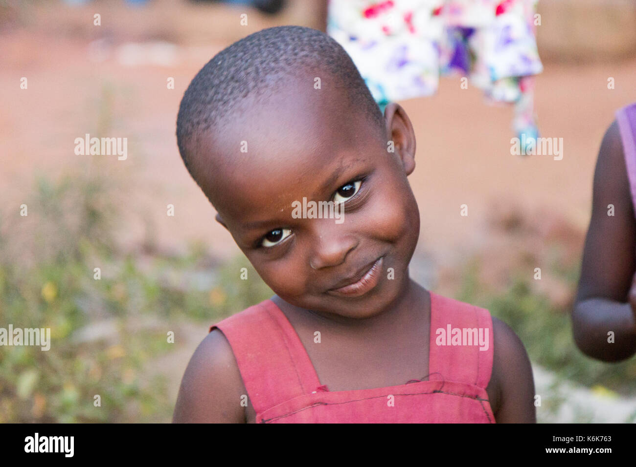 Un mignon petit black preteen girl âge incliner sa tête en souriant. Elle est vêtue d'une robe rouge. Banque D'Images