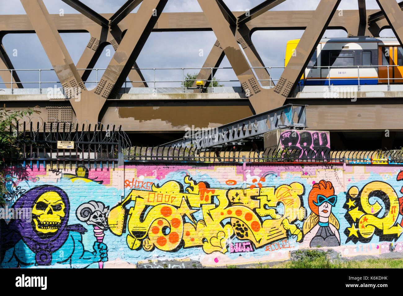 Scène urbaine de train (motion floue) pont passage passant mur recouvert de graffitis dans East London Banque D'Images