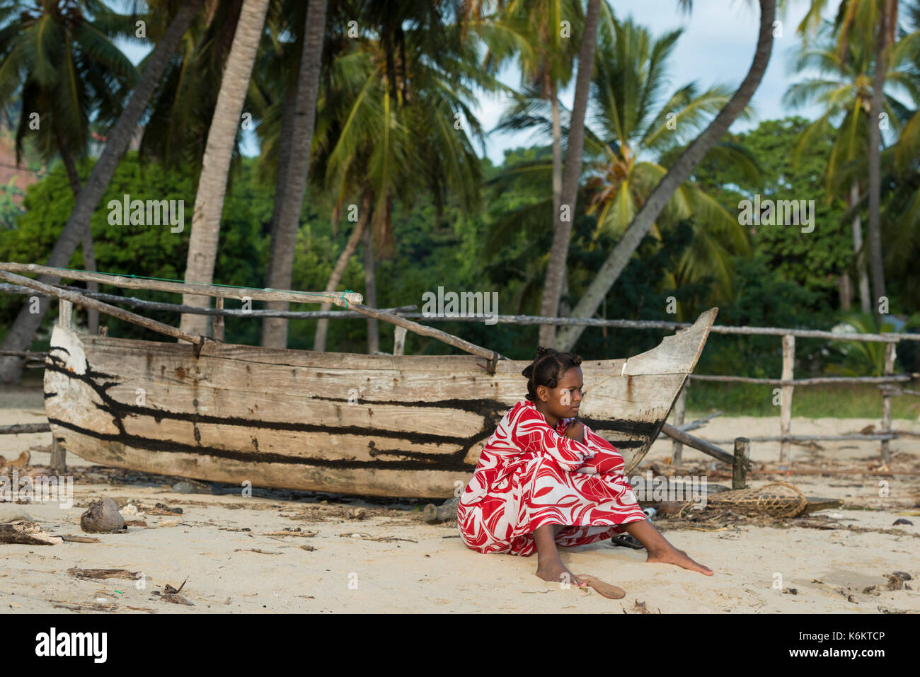 Femme assise sur la plage bordée de palmiers, Nosy Be, Madagascar Banque D'Images