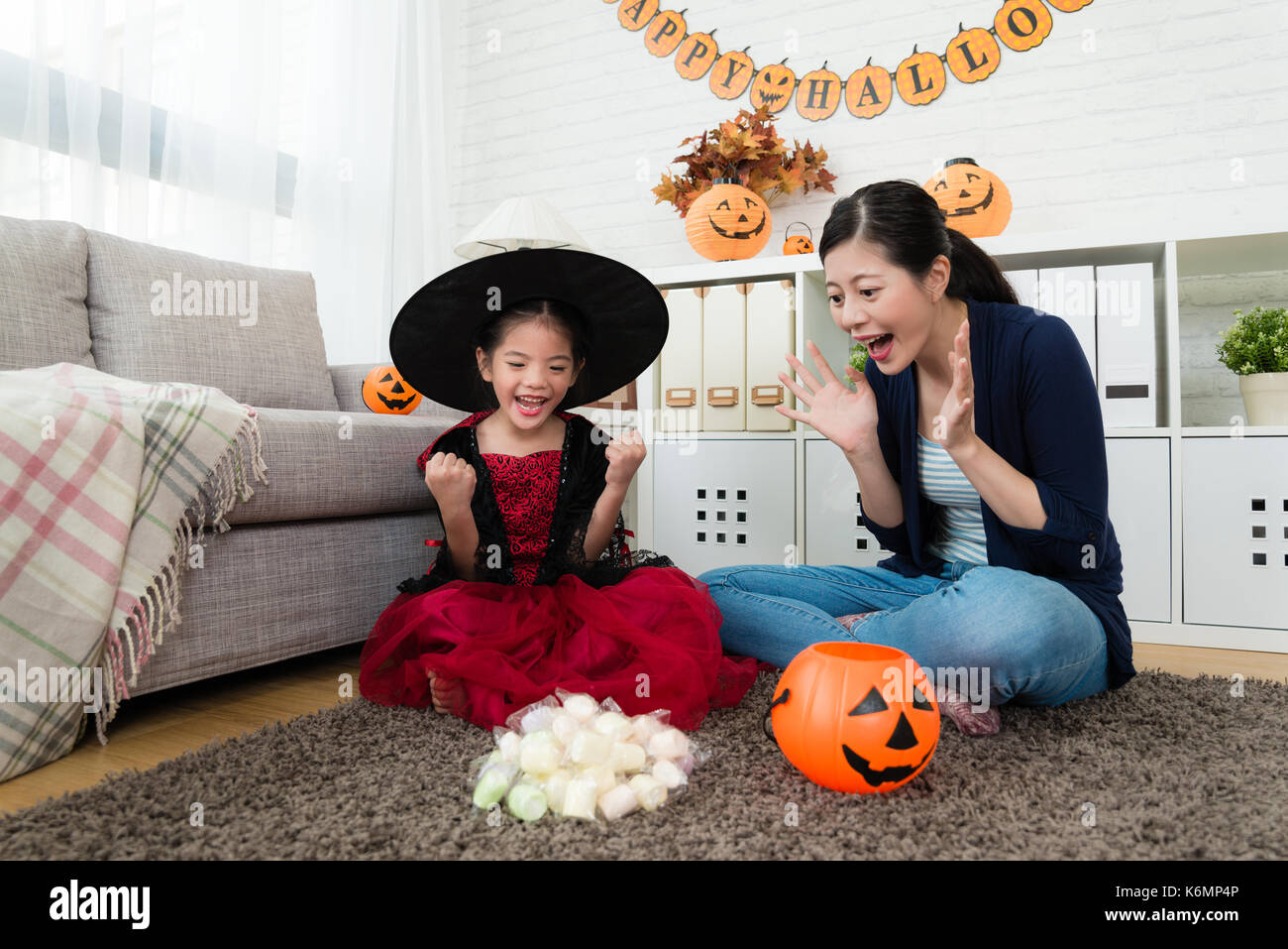 Happy girl le sentiment que la réussite et sa mère choquée de voir beaucoup de bonbons trick ou traiter le jeu de halloween Banque D'Images