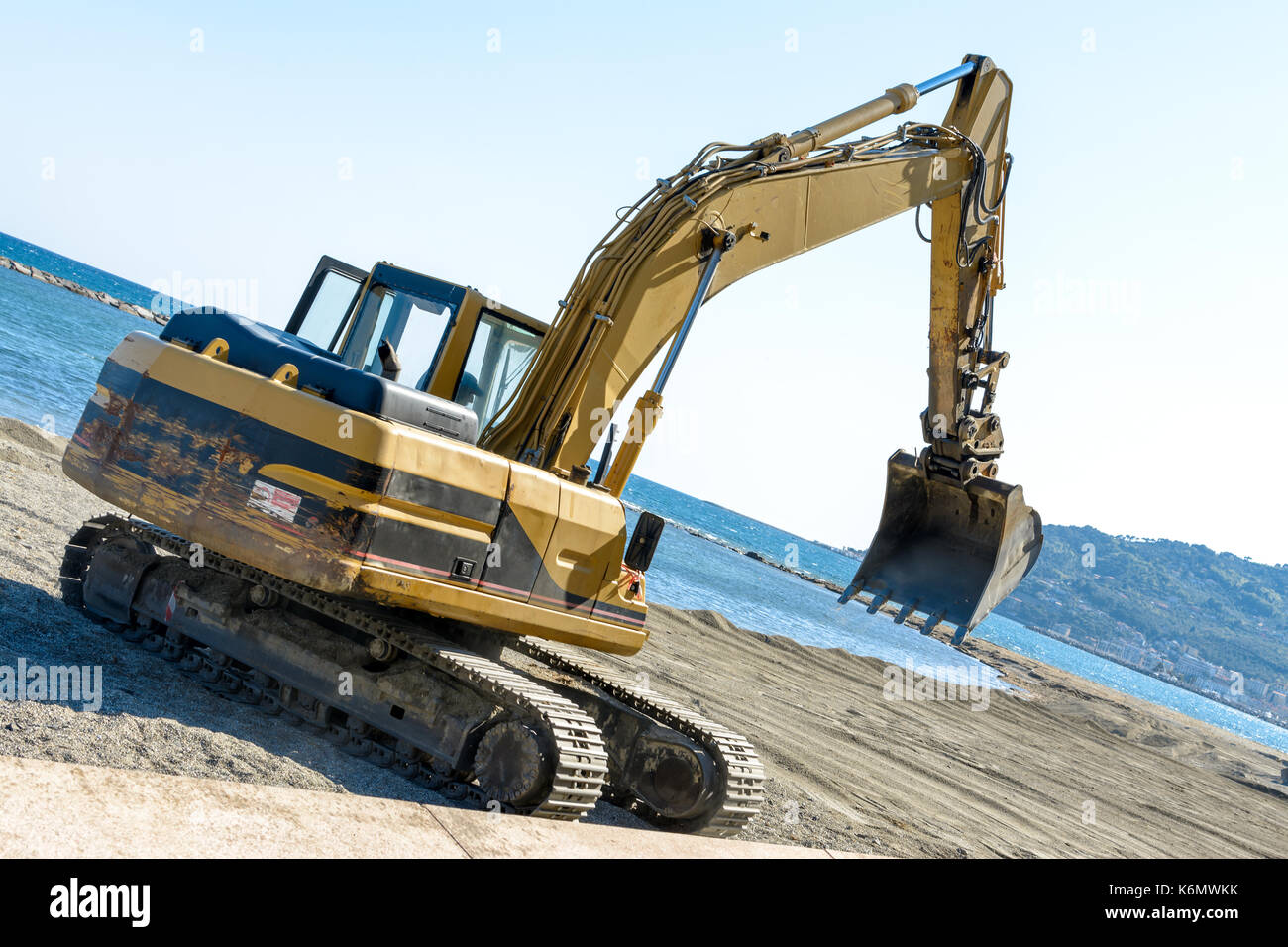 Que l'excavateur travaille sur la plage pour lisser le sable avant le début de la saison d'été Banque D'Images