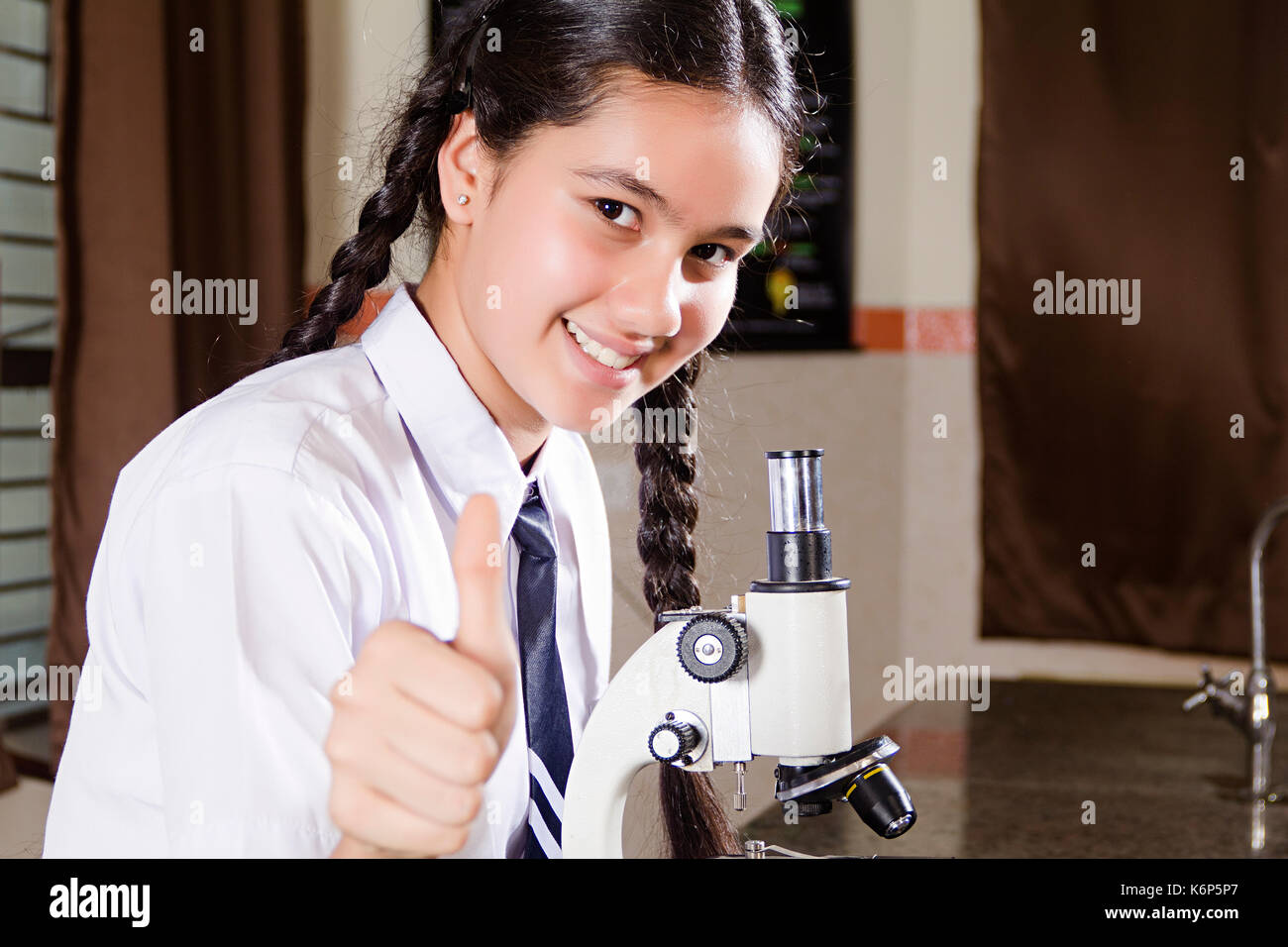 1 Indian School girl student microscope contrôle lab recherche science et showing Thumbs up Banque D'Images