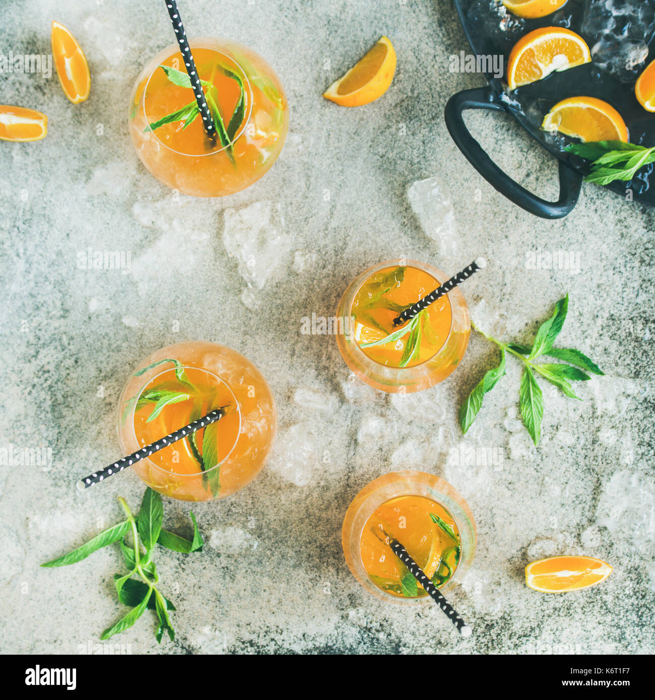 Boissons froides rafraîchissantes cocktail d'été à l'orange, menthe poivrée et de la glace concassée dans verres sur fond de béton gris, vue du dessus, Banque D'Images
