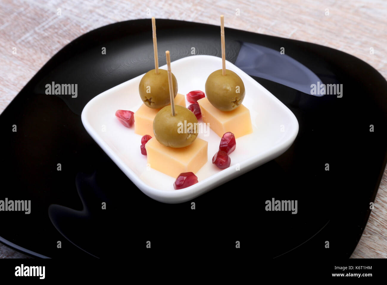 Canapés fromage aux olives et de grains de grenade sur plateau en bois close up. Banque D'Images
