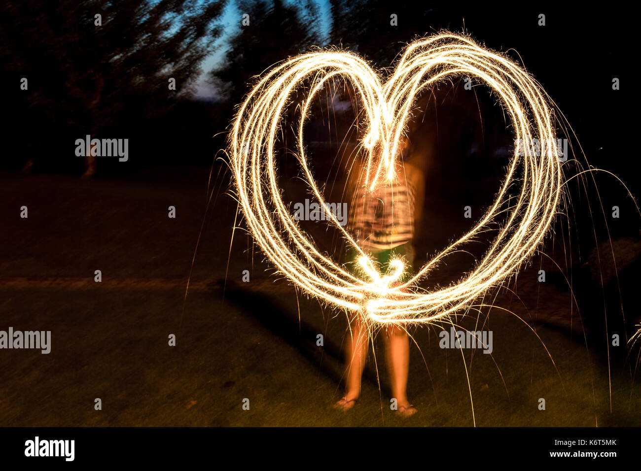 Une fille de coeur irrégulier avec feux de Bengale sparks. arrière-plan flou Banque D'Images