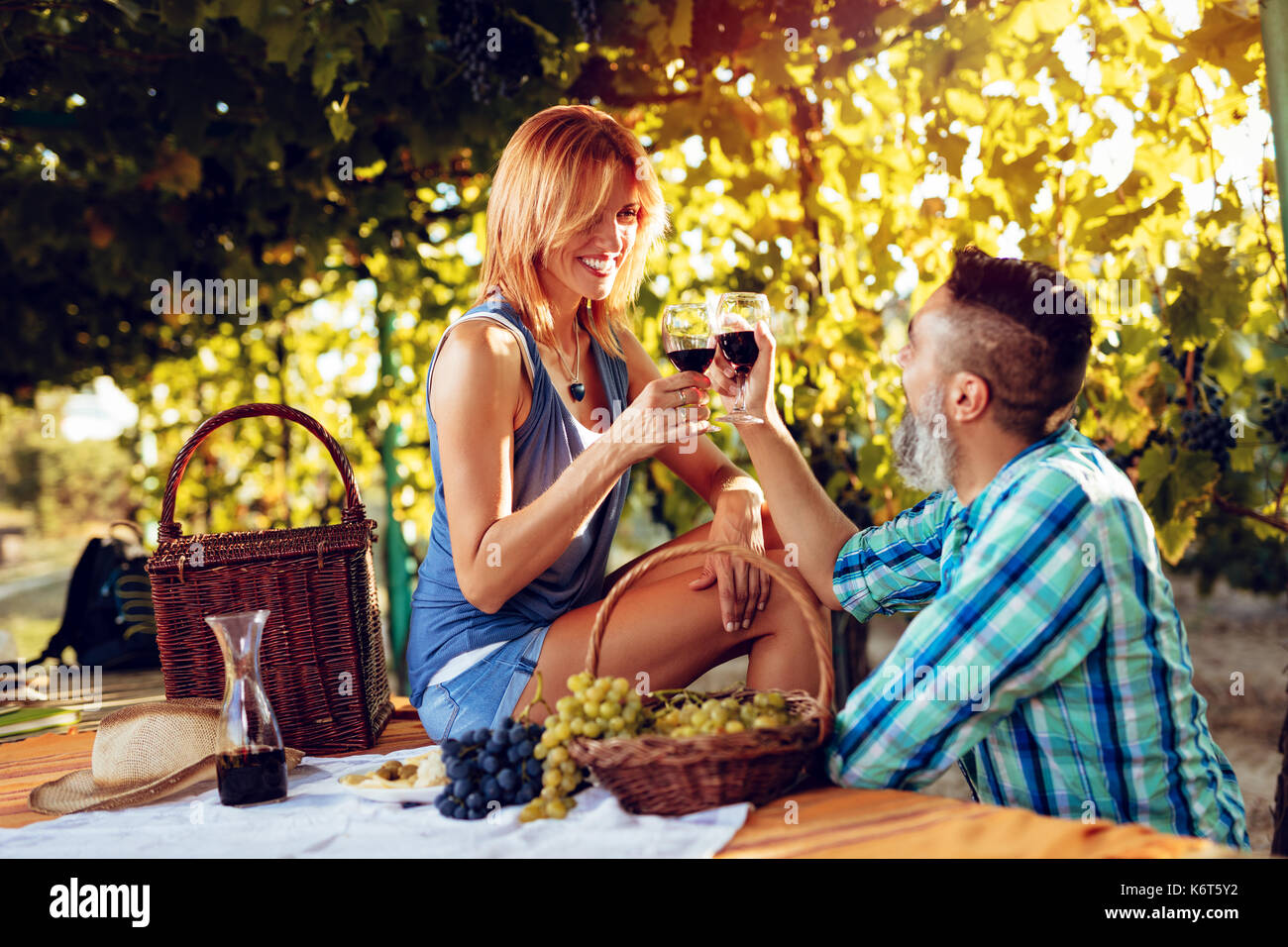 Beautiful smiling couple having picnic et dégustation de vins dans un vignoble. Banque D'Images