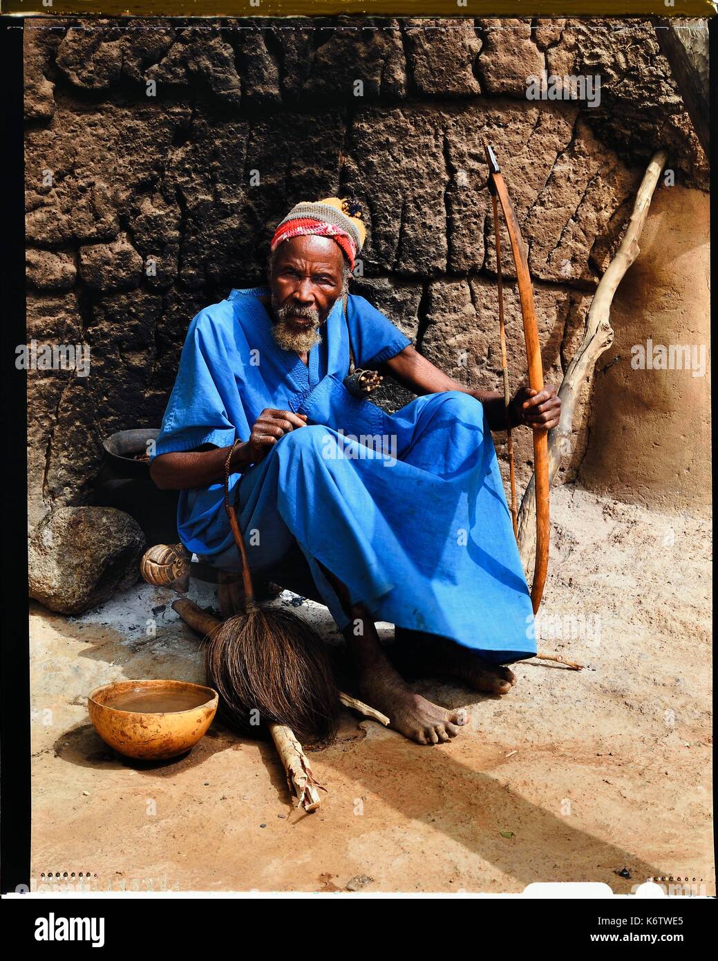 Le Burkina Faso, la province de Poni, terre LoropŽni Lobi, région, chef du village d'Ouadara posant avec ses attributs (arc et flèches, fly swatter) et une calebasse de bière de mil (céréale) Banque D'Images