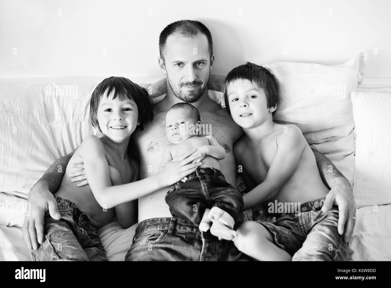 Père de trois garçons, l'éducation préscolaire, l'enfant et du nouveau-né, bébé assis au lit, serrant ensemble Banque D'Images