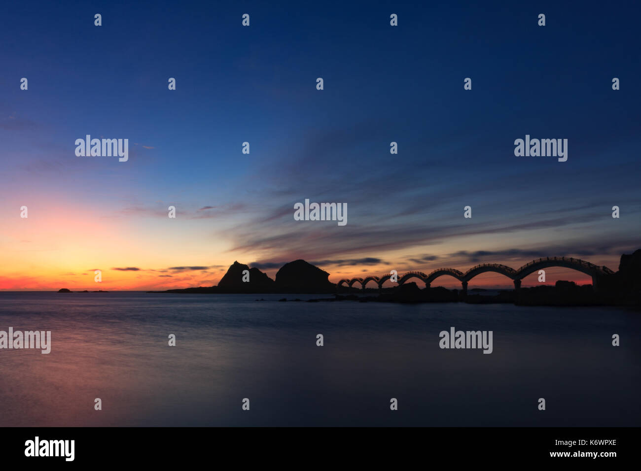 Une petite île au large de la côte et l'emblématique passerelle à huit arcs silhoueté contre le ciel crépuscule, à Sanxiantai à Taitung, Taiwan Banque D'Images