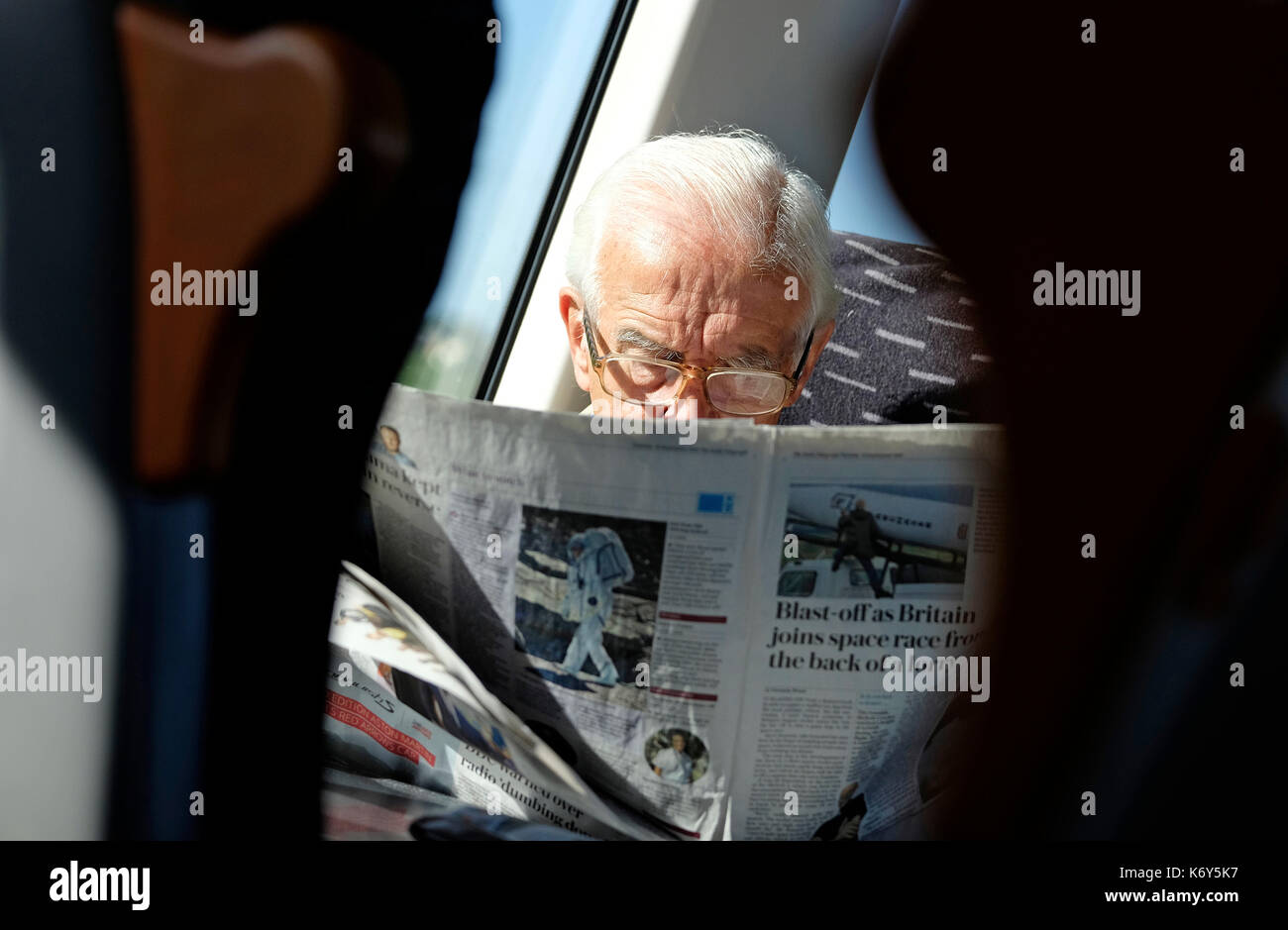 Senior man reading newspaper on train Banque D'Images