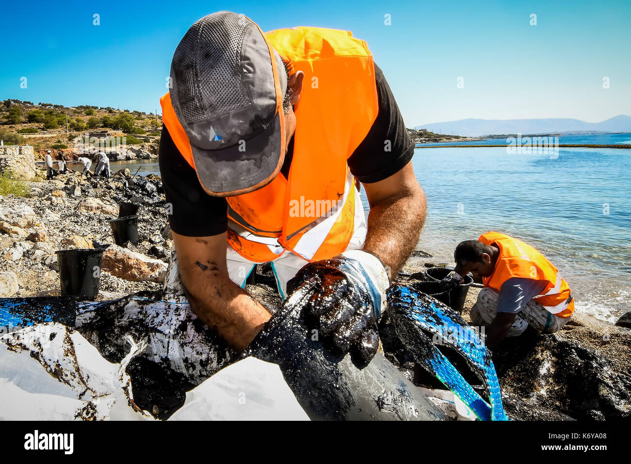 Salamine, Athènes, Grèce - 13 septembre 2017 : Les travailleurs tentent de nettoyer l'huile qui est lavé à terre, sur une plage de l'île de Salamine, près d'Athènes après un vieux ta Banque D'Images