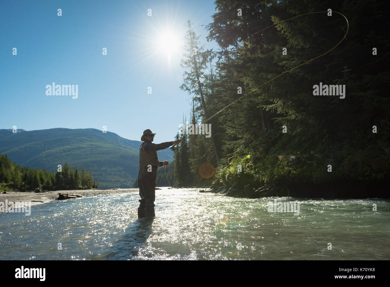 Jeune homme pêche casting road à river au cours de journée ensoleillée Banque D'Images