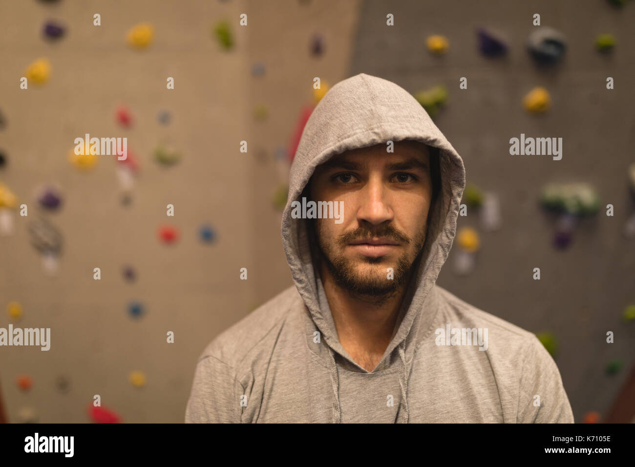 Portrait de l'athlète masculin portant des T-shirt tout en se tenant par le mur d'escalade en salle de sport Banque D'Images