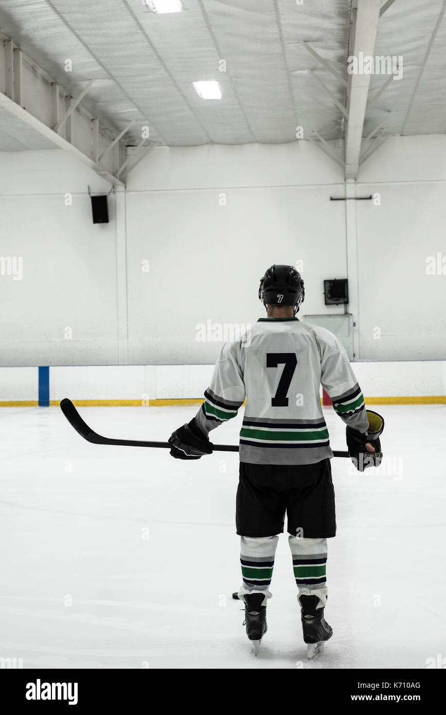 Vue arrière du joueur de hockey sur glace masculin holding stick tout en se tenant au rink Banque D'Images