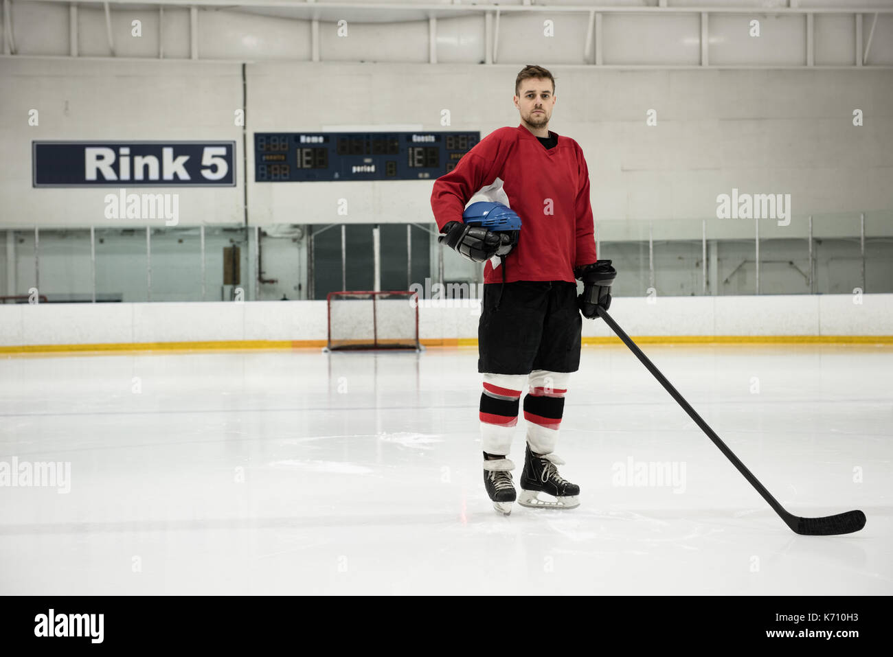 Portrait de joueur de hockey sur glace masculin holding helmet et bâton à rink Banque D'Images