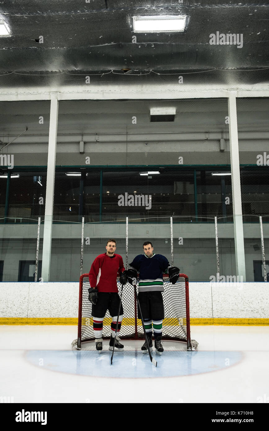 Toute la longueur de joueurs de hockey sur glace masculin debout près de poteau de but at rink Banque D'Images