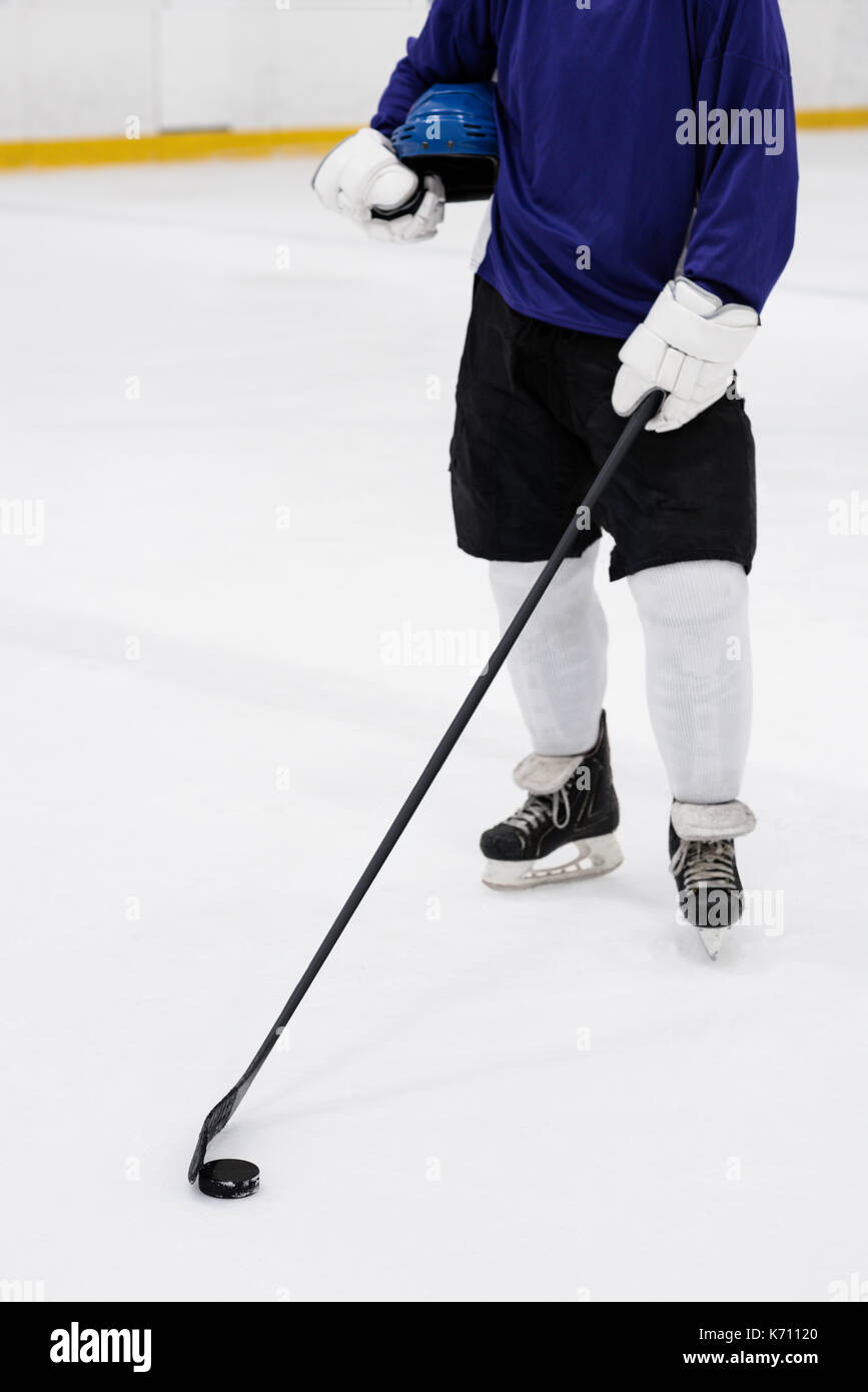 La section basse de joueur de hockey sur glace masculin avec bâton debout à rink Banque D'Images