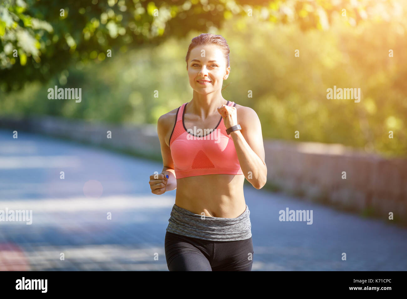 Young smiling sporty woman running in park le matin. fitness jogging girl in park Banque D'Images