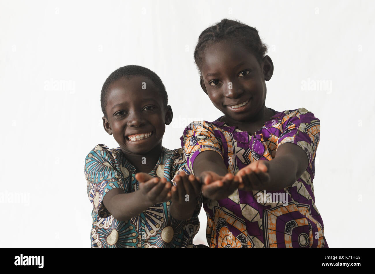 Deux enfants africains montrant leurs paumes la mendicité pour demander quelque chose, tout en souriant, isolated on white Banque D'Images